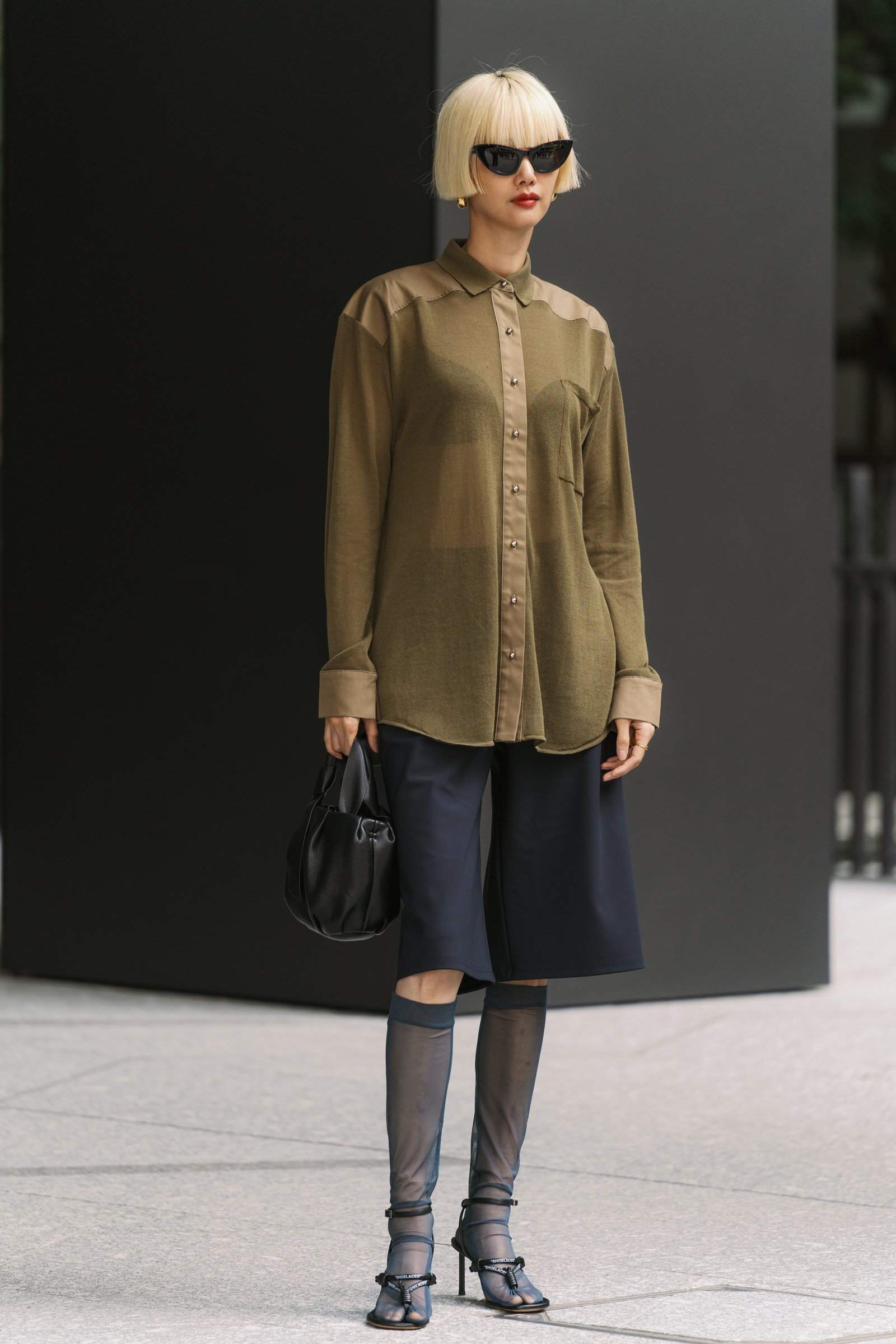 Photo of Tokyo street style with model wearing black bermuda shorts.