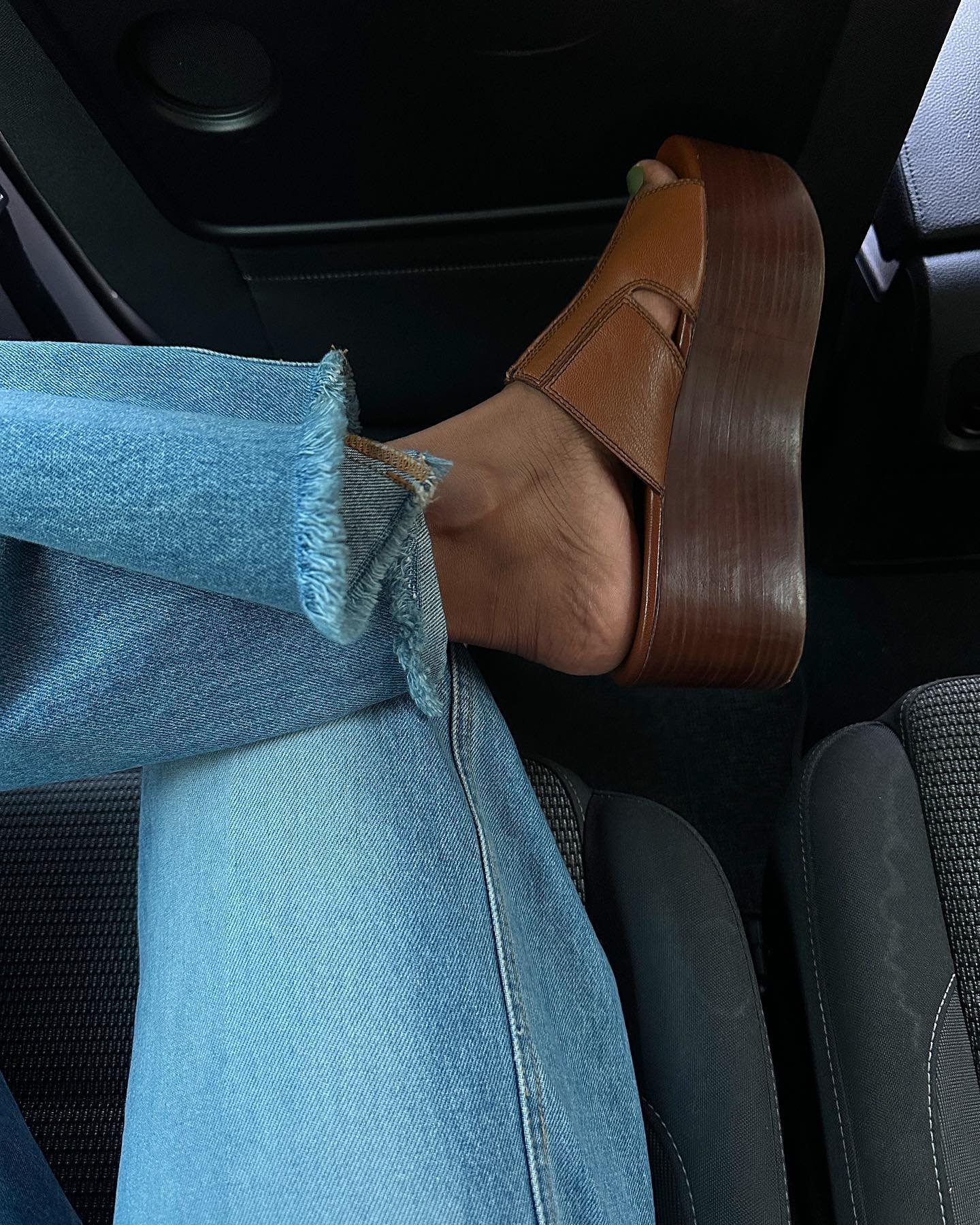 @monikh wears a pair of wooden wedge shoes with blue jeans whilst sitting in the back of a car