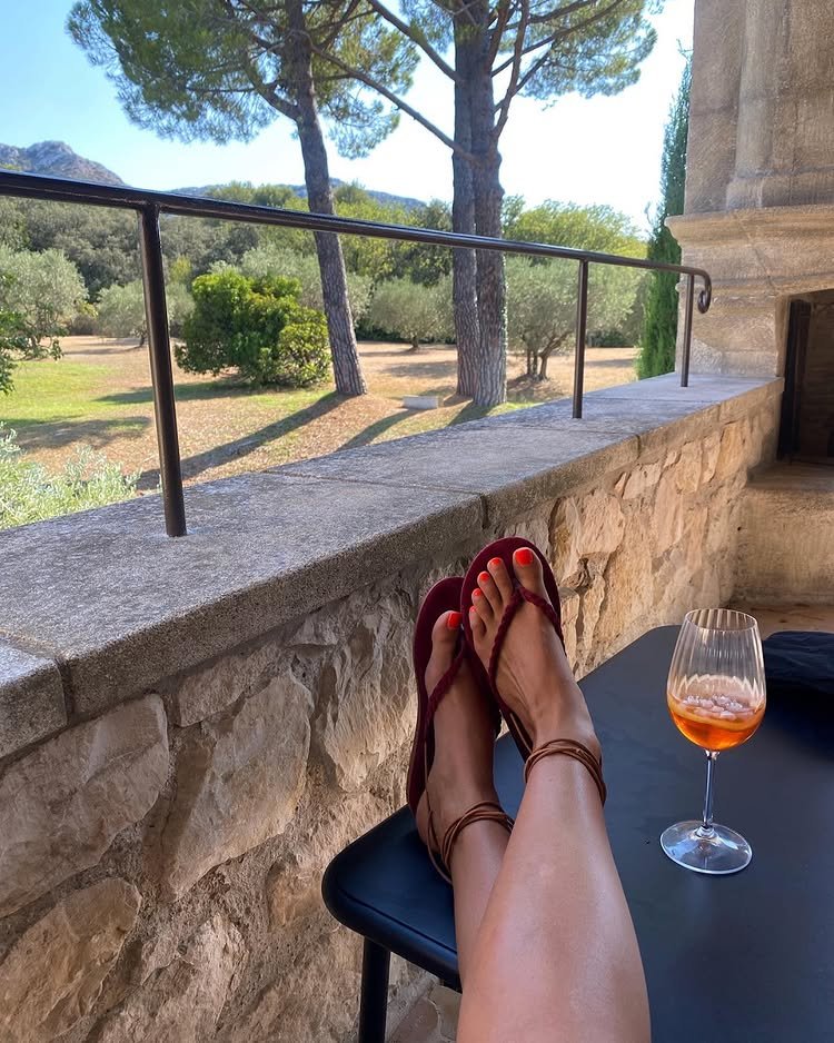 @smythsisters wears a pair of tan ankle-tie sandals whilst drinking an Aperol Spritz