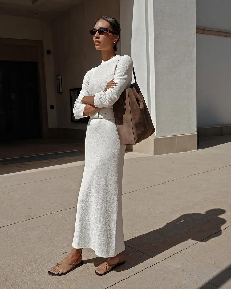 @tylynnnguyen wears a cream dress with slim strap sandals and a tan suede tote bag