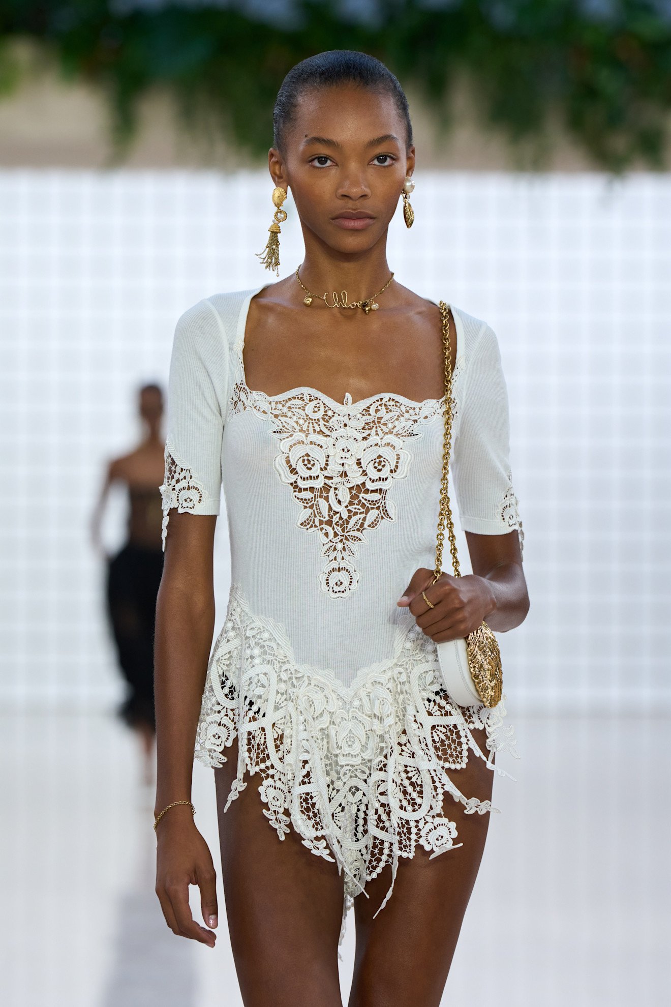 A woman wears tassel accented earrings on the chloe s/s 25 runway.