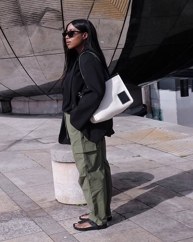 @_loissterling wears a pair of khaki cargo trousers with flip flops and a black jumper
