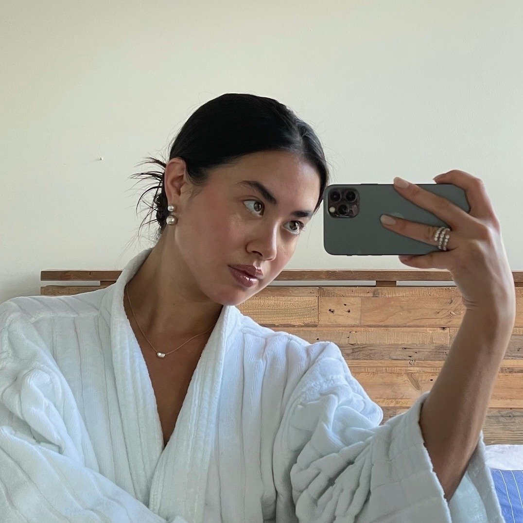 Woman taking a mirror selfie with an iPhone.