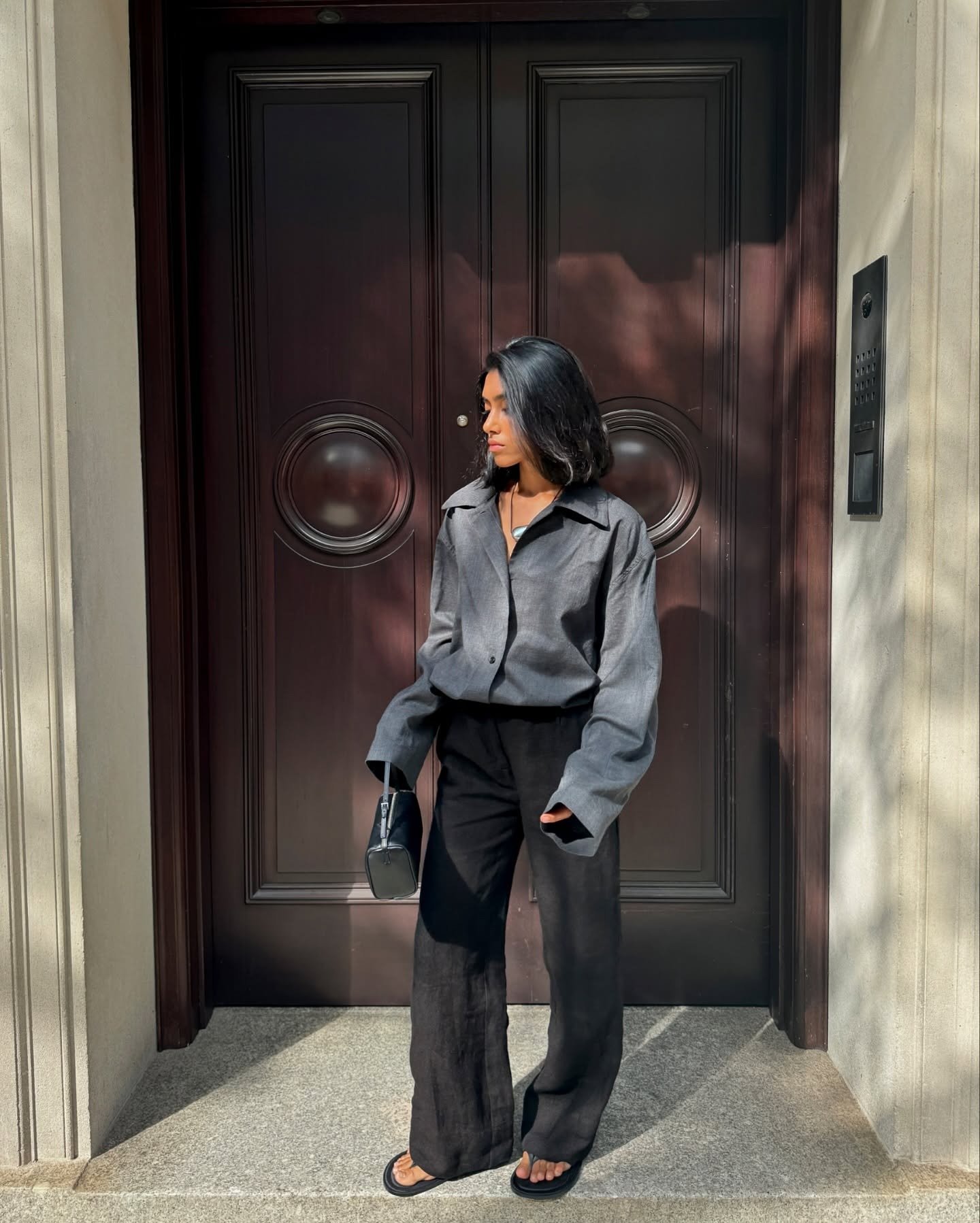 @shayinjune wearing a gray button-down shirt with black trousers and flip-flops.