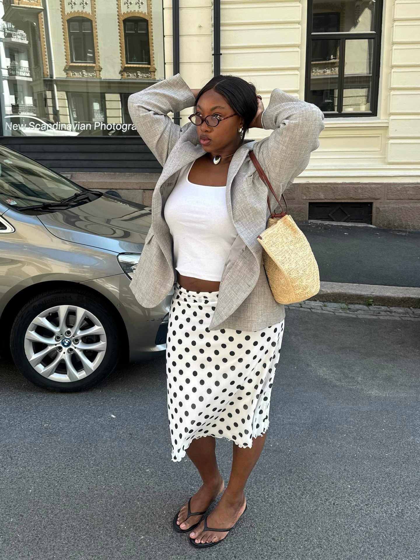 Fashion person Nennae wears the awkward midi skirt trend in a polka dot iteration. Paired with a white halter neck , linen blazer and raffia bag in a recent image taken from her Instagram.