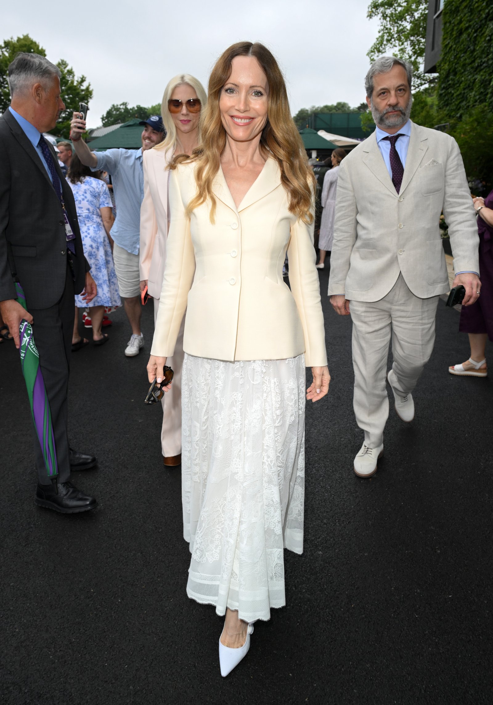 Lesley Mann wears a cream blazer and white lace skirt with a pair of white pointed toe shoes
