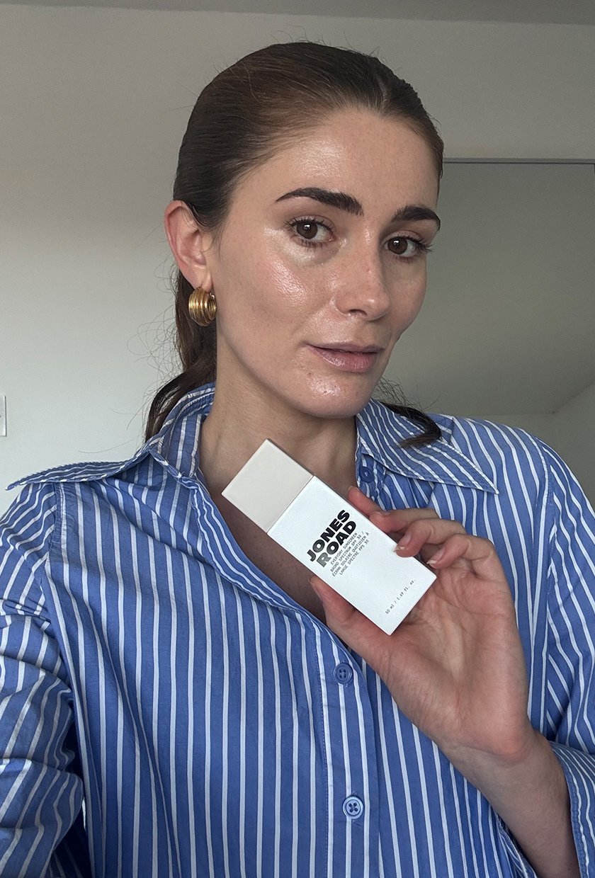 Eleanor taking a selfie while holding in Jones Road Everyday Sunscreen in shade sandy