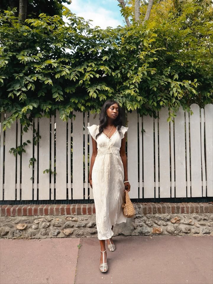 @emmanuellek_ wears a pair of white heeled T-bar sandals with a white midi dress