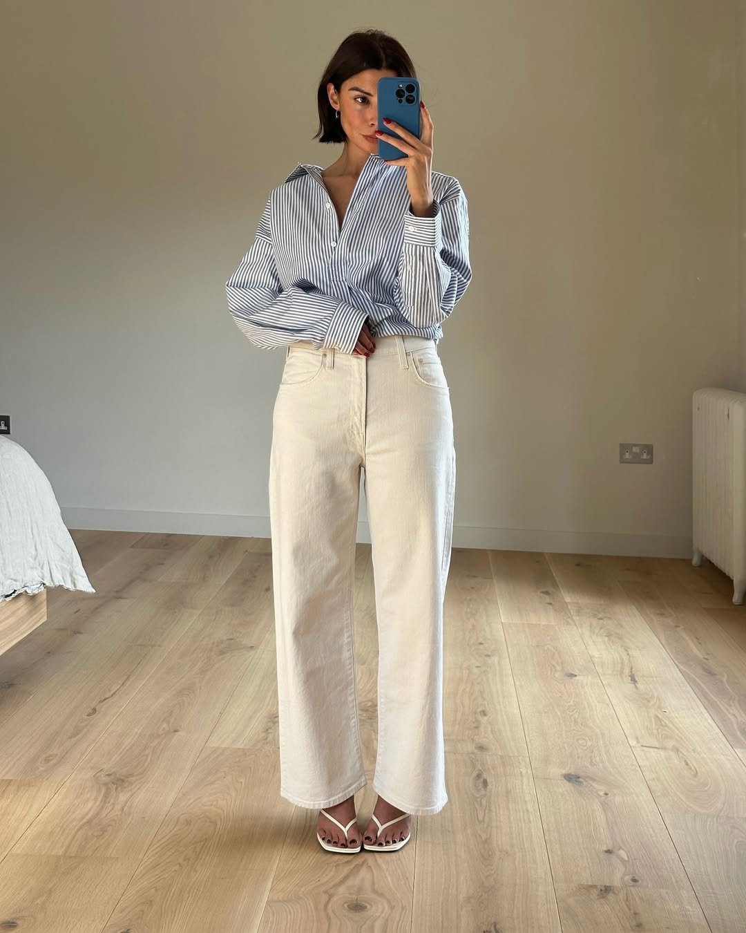 @smythsisters wears a blue striped shirt, white jeans and white heeled flip-flops