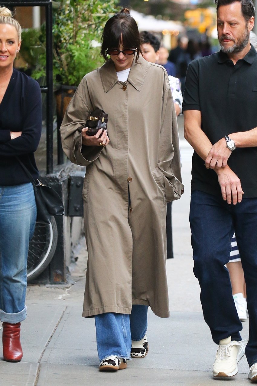Dakota Johnson wearing a trench coat, jeans, and Adidas Taekwondo cow sneakers in NYC