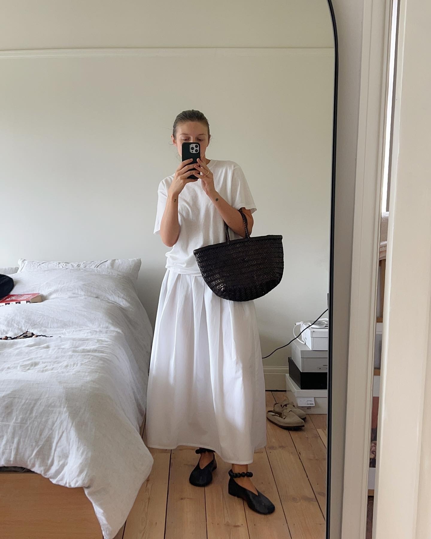 Influencer @brittanybathgate wears a white skirt with black ballet flats, a white t-shirt and a black bag.