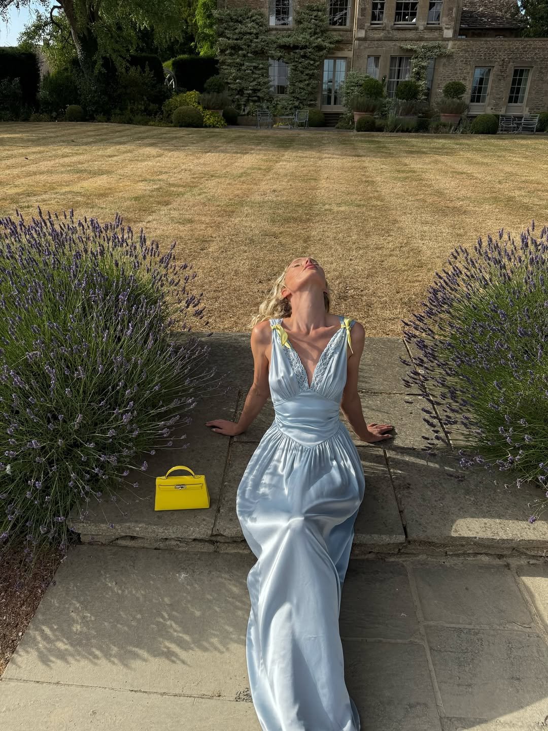 @hoskelsa wears a light blue satin maxi dress with a yellow handbag