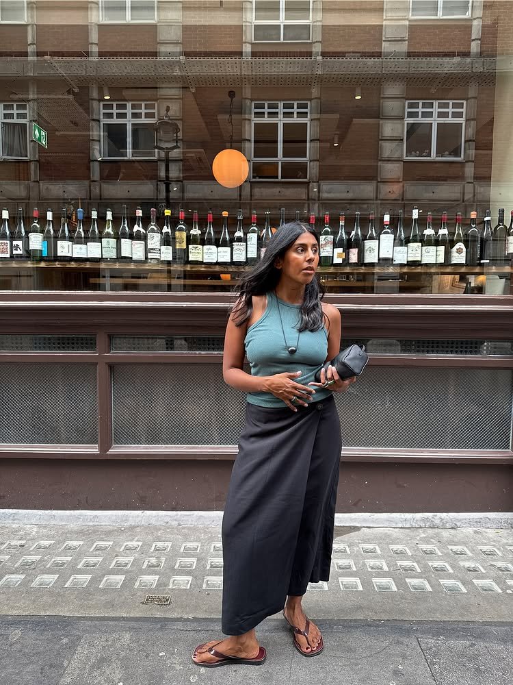 @monikh wears a teal tank top with a black wrap-around linen skirt