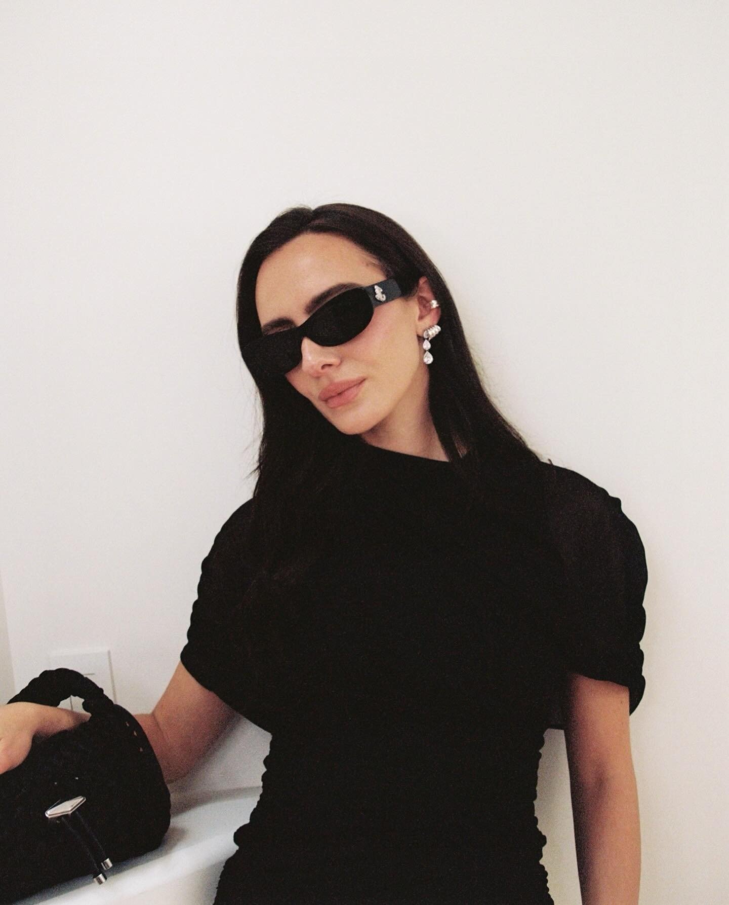 A woman wearing a black dress and black sunglasses