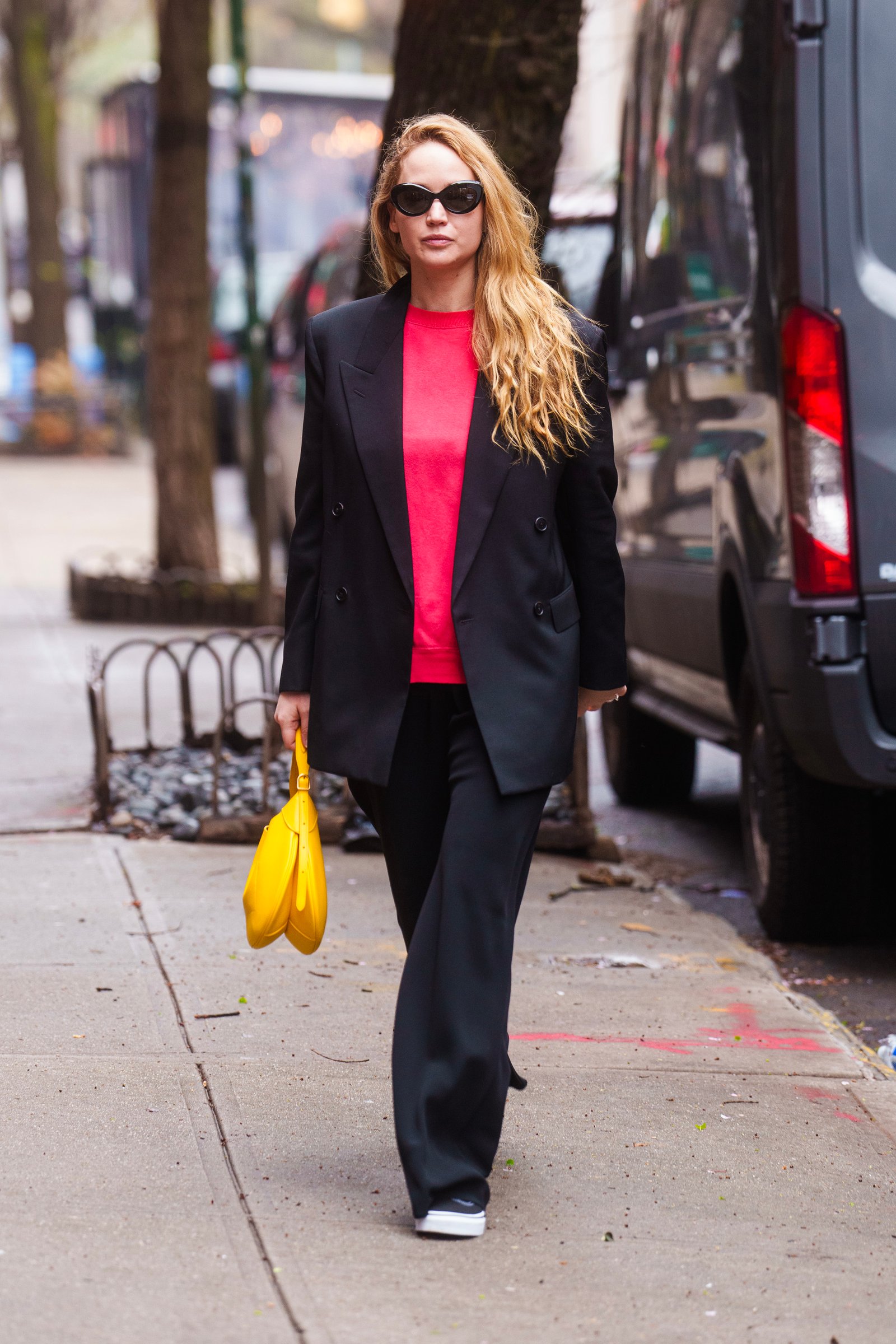 An image of Jennifer Lawrence wearing a red t-shirt with black trousers, Vans shoes and a blazer while out in NYC.