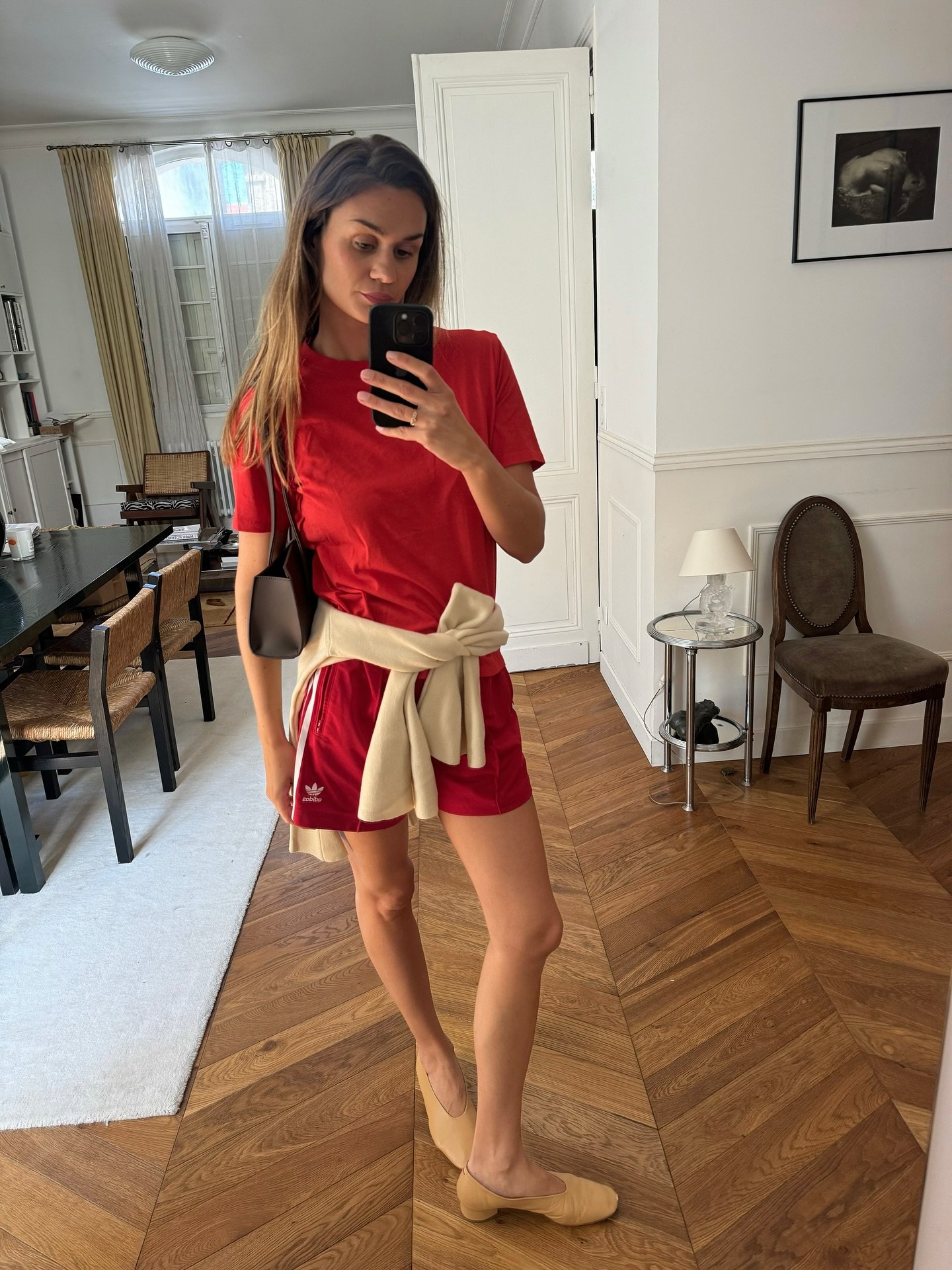 An image of @annelauremais wearing the red top trend with athletic shorts and suede ballet pumps while in Paris.