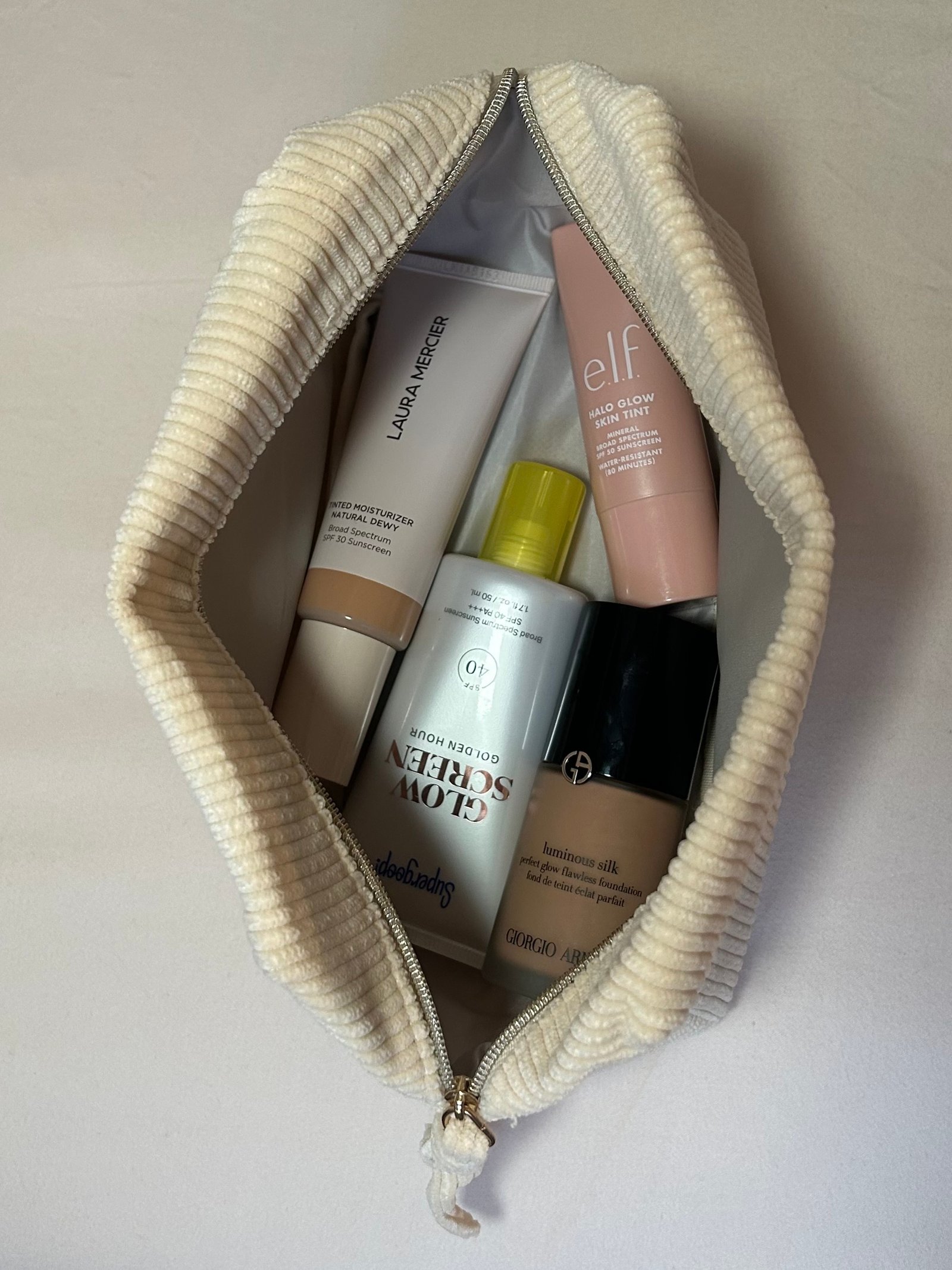 Alyssa Brascia's favorite foundations, tinted moisturizers, and sunscreens in a travel makeup bag.