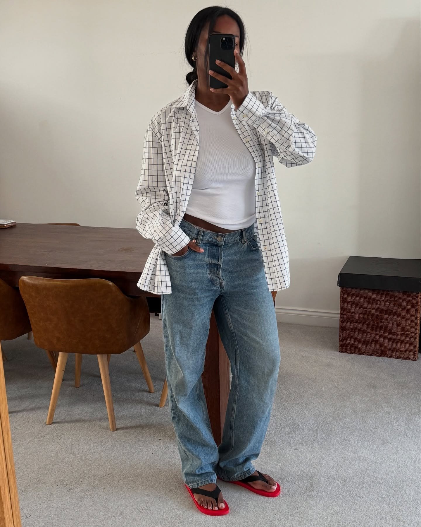 European influencer wearing a button-down shirt, white tank top, baggy jeans, and The Row flip-flops
