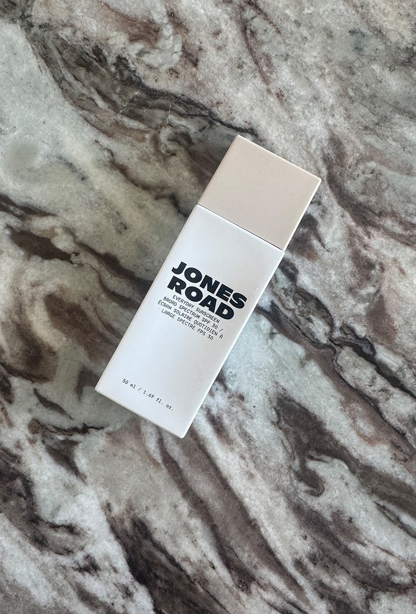 Jones Road Everyday Sunscreen bottle in shade Sandy on a marble table
