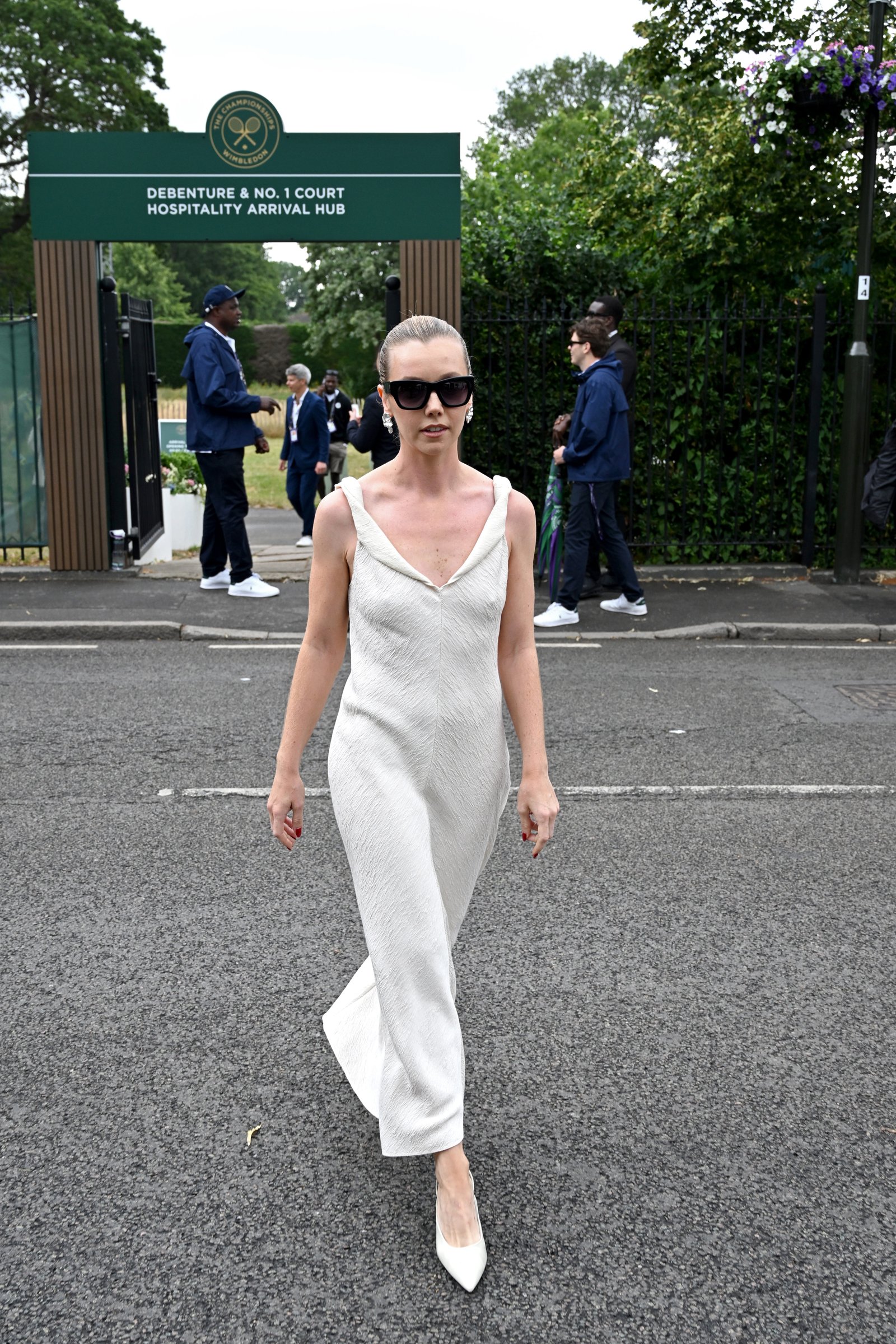 Lauren Lyle wears a white strappy dress with a pair of white pointed toe shoes