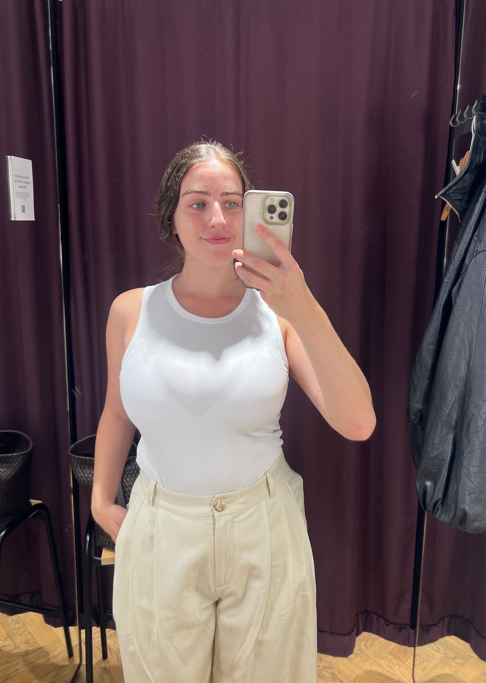 An image of Who What Wear's Ava Gilchrist wearing an & Other Stories white tank top with pleated trousers.