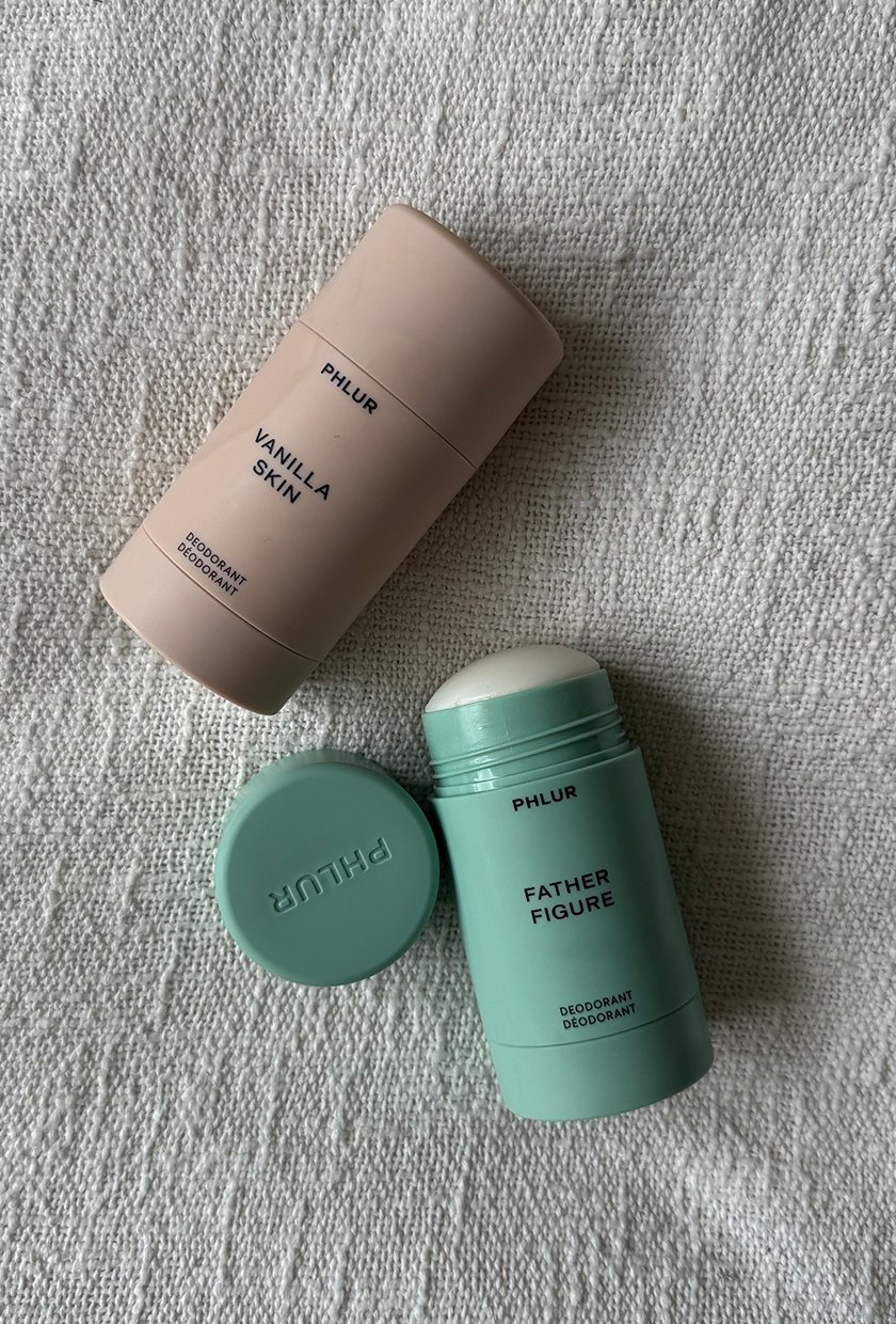 A photo of the Phlur Vanilla Skin and Father Figure deodorants on a blanket
