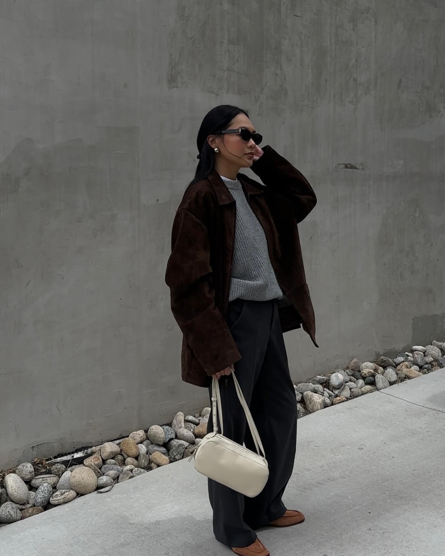 Influencer @dawn.tan wears slouchy jeans with tan suede loafers, a grey jumper and a brown suede leather jacket.