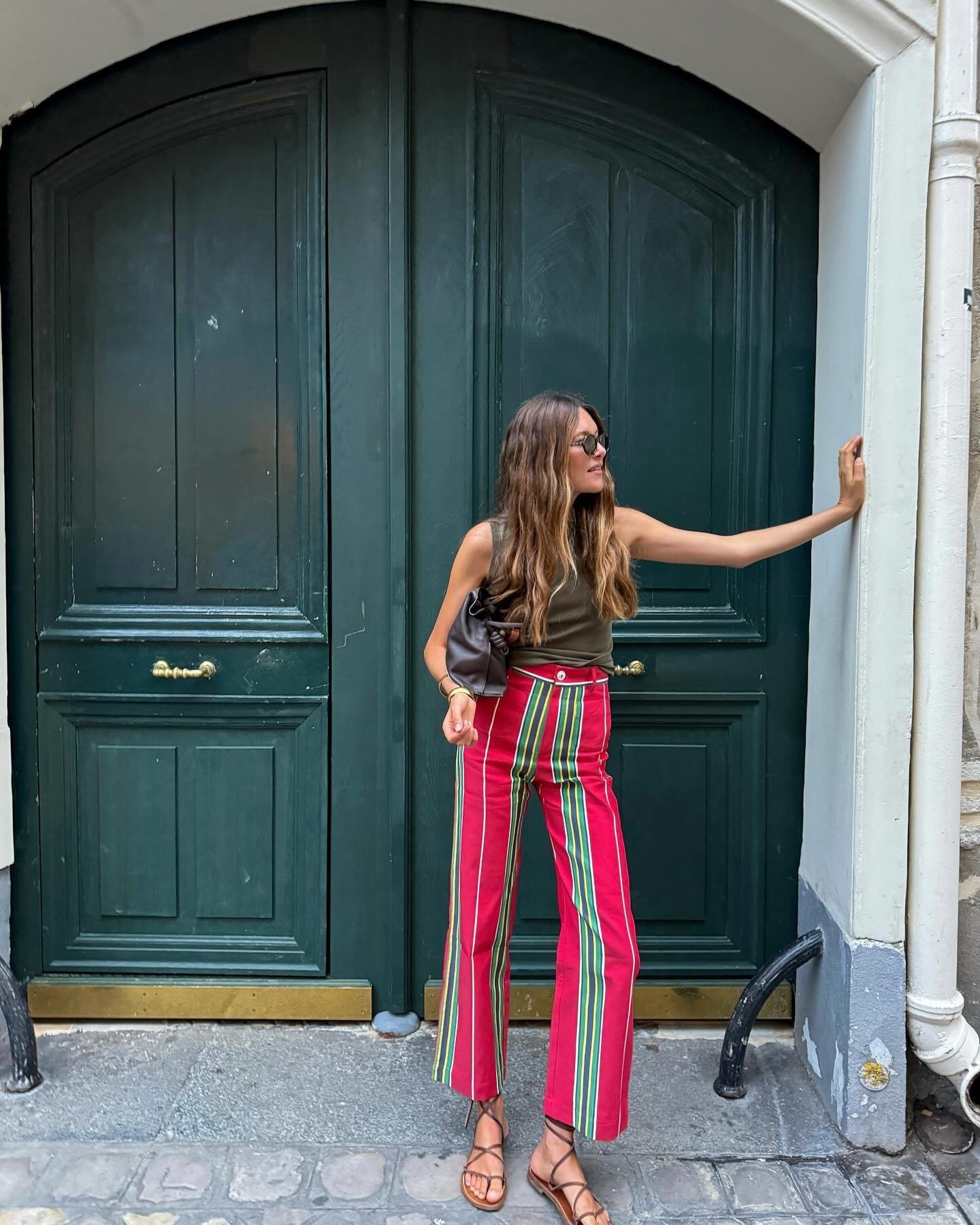Influencer Sara wears red striped pants with a green tank.