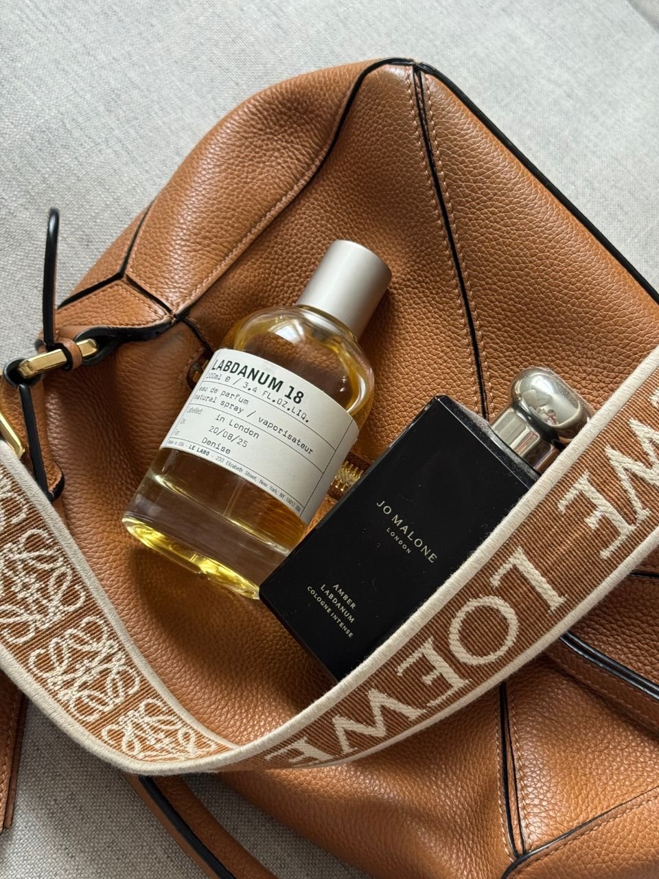 An image of two labdanum perfumes displayed on top of a leather purse